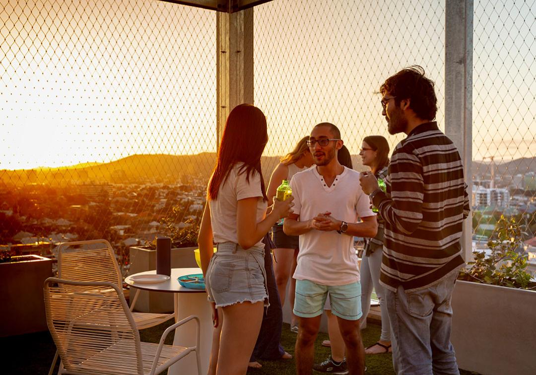 Students gather on a rooftop to socialise during sunset.