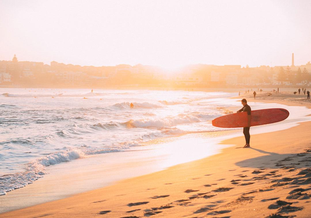 A surfer approaches waves at an Australian beach.