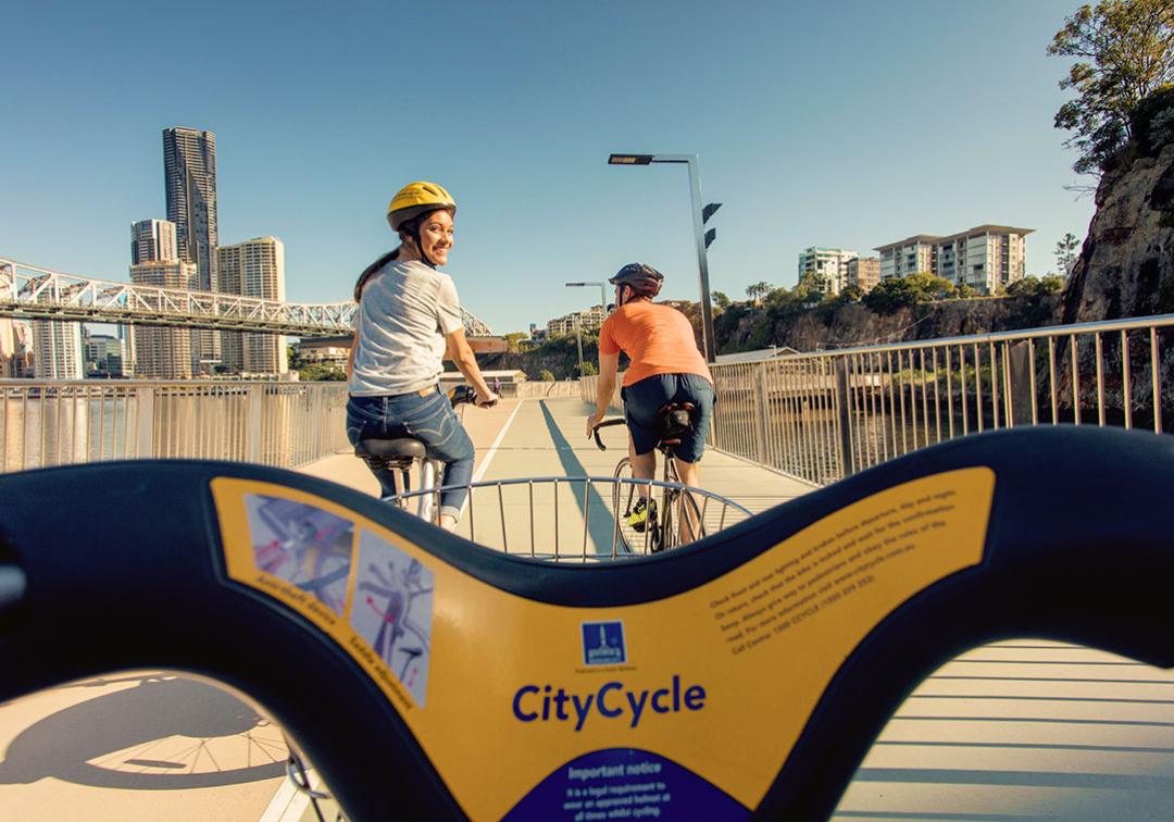 Cyclists using CityCycle to cross a pedestrian bridge over the Brisbane River.