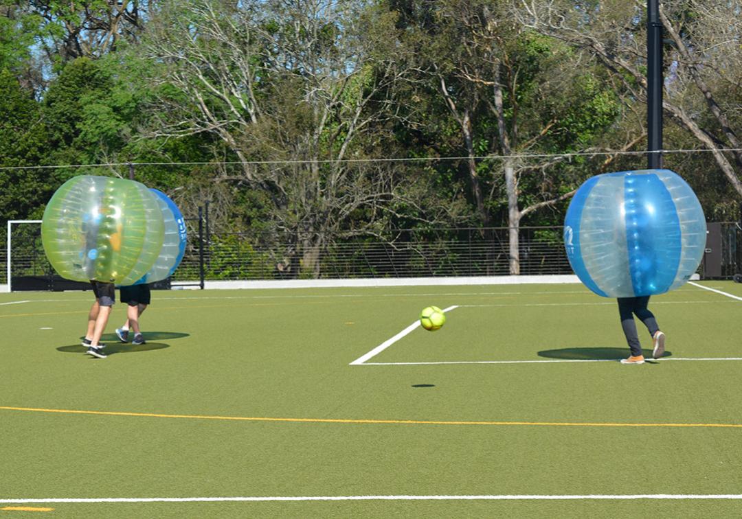 A team of bubble football players bounce off each other on the synthetic playing fields at St Lucia campus.