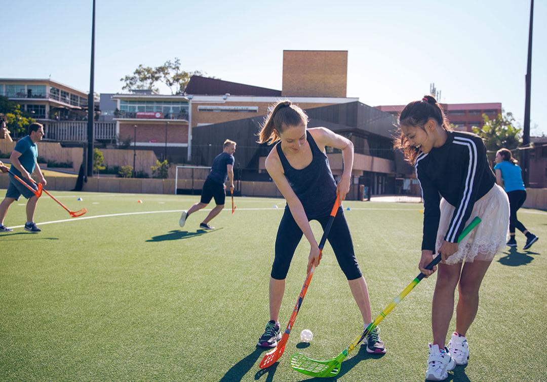Two students playing hockey on the Synthetic Playing Fields at St Lucia campus.