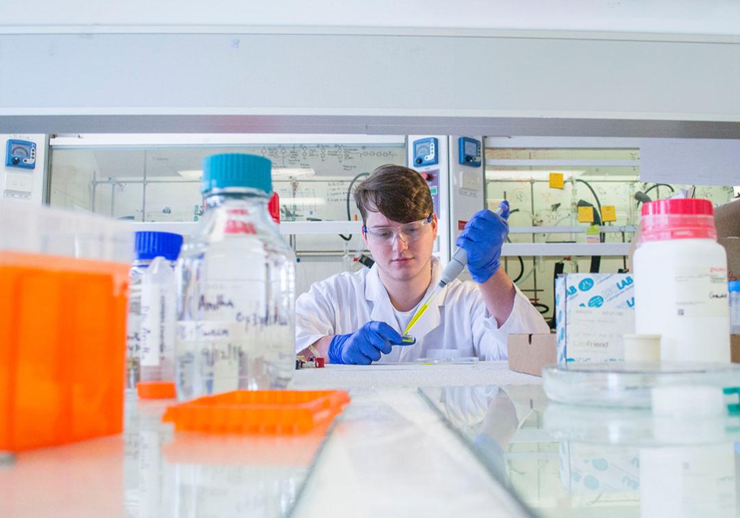 Biology student surrounded by colourful lab equipment. 