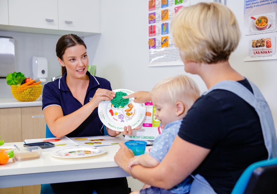 Dietician using food props and speaking with mother and child. 