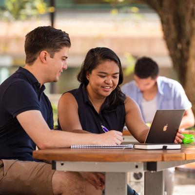 Two students sitting outside looking at laptop