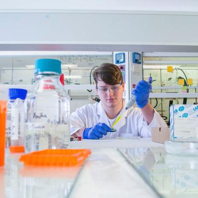 Biology student surrounded by colourful lab equipment. 