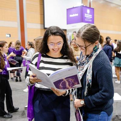 A high school student and her parent look at a UQ study brochure