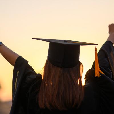A graduate with their hands in the air