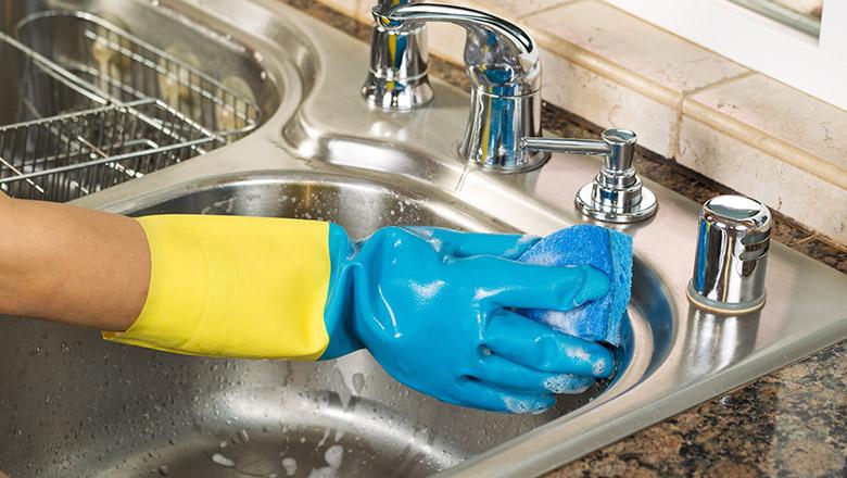 Closeup of hand with glove on cleaning sink