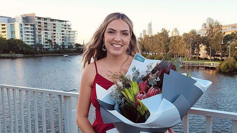 Nicole Petzer standing in front of river with flowers after graduation