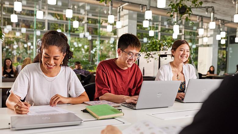 UQ students study with laptops in a light-filled classroom with greenery in background